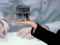 Model domu na dłoni, podczas gdy ktoś podpisuje dokumenty. Kluczowe pytanie: do kiedy rozliczenie za wynajem mieszkania?