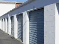 Rząd niebieskich, metalowych bram garażowych z numerami 46 i 47. Zastanawiasz się, ile kosztuje wynajem garażu?