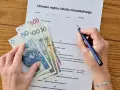 Umowa najmu i pieniądze na stole. Zastanawiasz się, jak zapłacić podatek od wynajmu mieszkania? Dokument i gotówka sugerują, że to czas na rozliczenie.