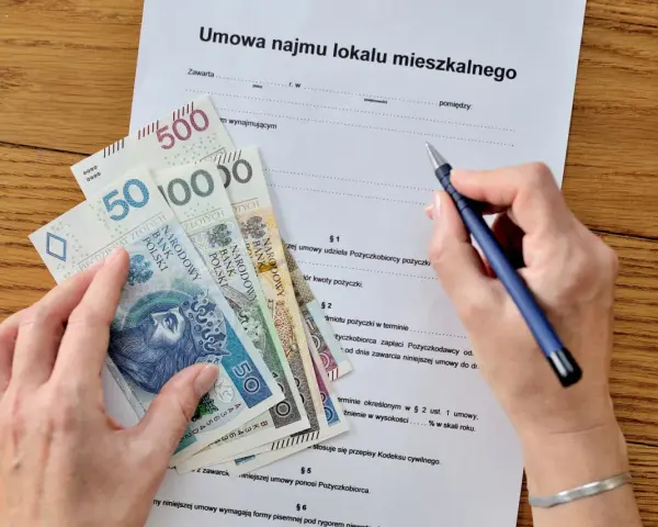 Umowa najmu i pieniądze na stole. Zastanawiasz się, jak zapłacić podatek od wynajmu mieszkania? Dokument i gotówka sugerują, że to czas na rozliczenie.